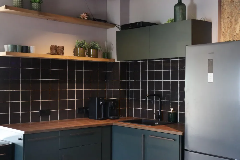 Saliegroene keuken met zwarte tegels