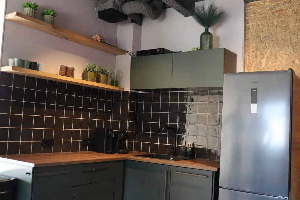 Keuken met zwarte tegels en groene kasten