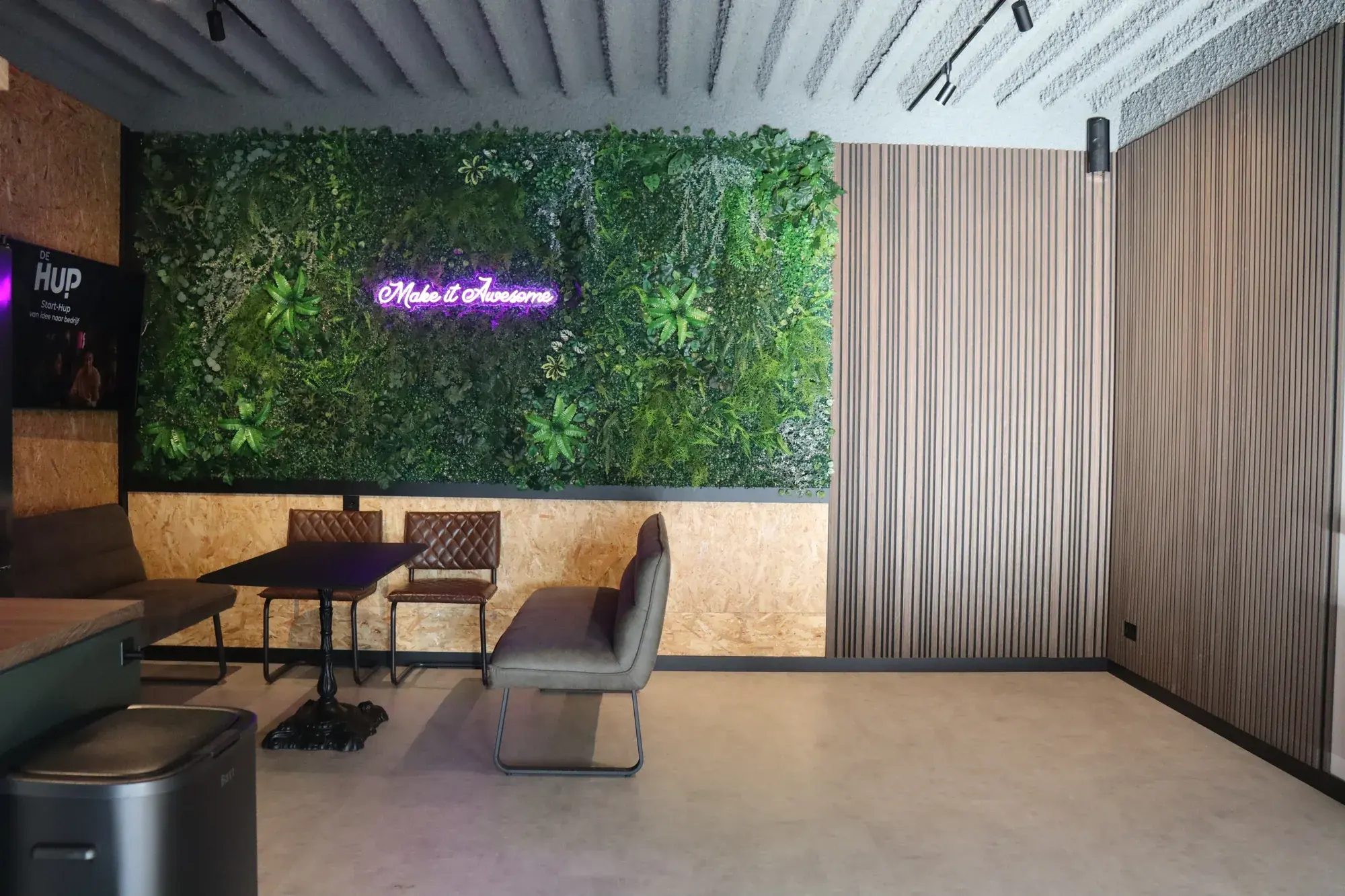 De lounge met plantenwand en neonbord