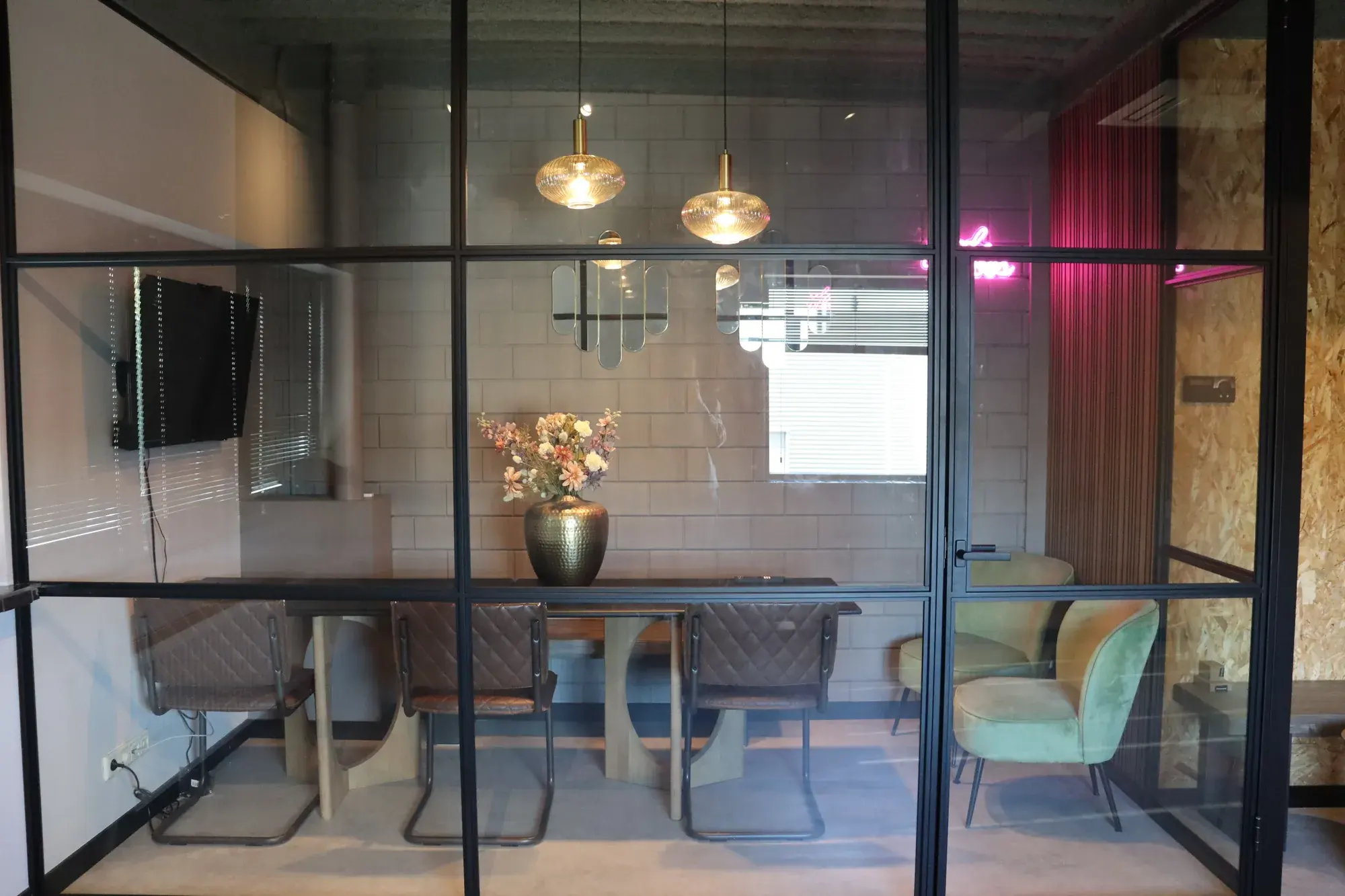 Overlegruimte achter stalen glaswanden met roze neon